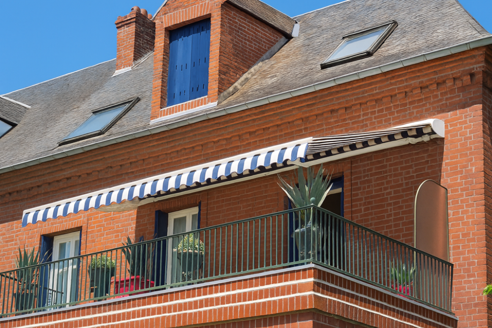 Store banne Jade pose façade aux Andelys (27) – structure blanche toile rayée blanc et bleu