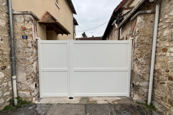 Portail battant en aluminium blanc posé entre piliers en pierre à Vernon dans l’Eure