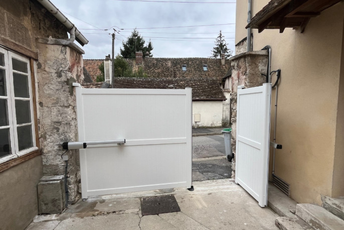 Portail battant aluminium blanc en cours d’ouverture à Vernon dans l’Eure
